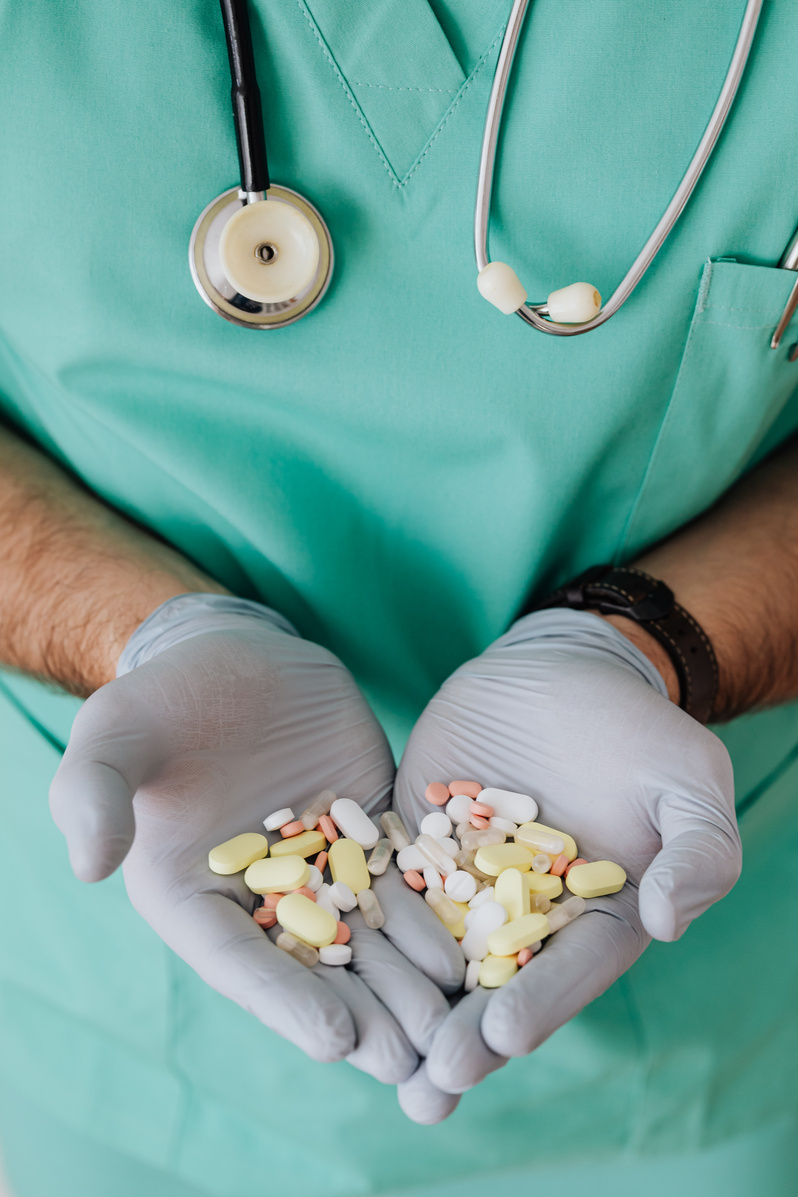 Crop man doctor showing pills in clinic